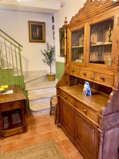 Mueble de madera vintage en una sala con escaleras y decoración en pared.