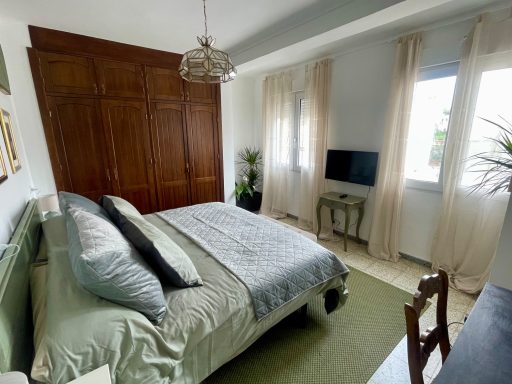 Habitación luminosa con cama doble, televisión y decoración sencilla.