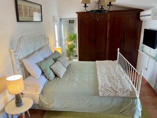 Habitación acogedora con cama, lámpara, armario y decoraciones verdes.