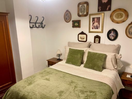 Habitación acogedora con cama de sábanas verdes y decoración en la pared.